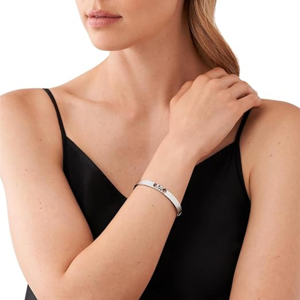 Platinum-plated bangle bracelet worn on wrist with MICHAEL KORS logo