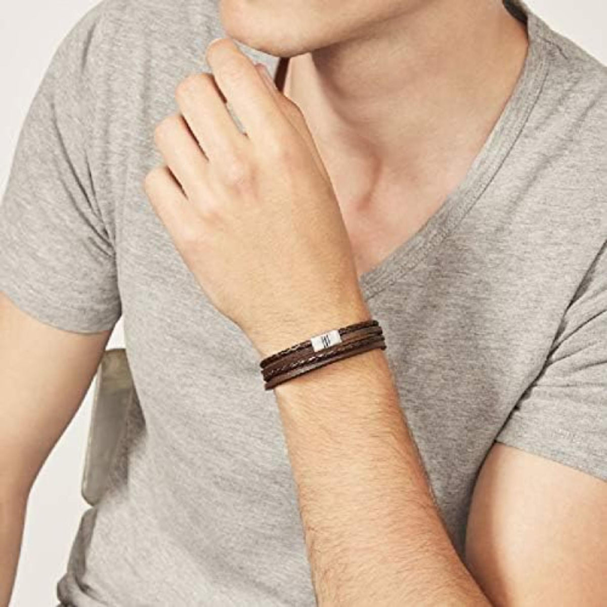 Men's dark-brown braided leather bracelet on wrist with silver clasp accents