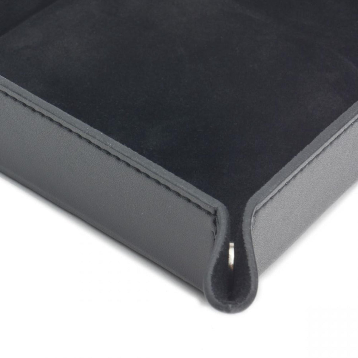 Black leather coin tray corner with stitched seam and folded edge detail.