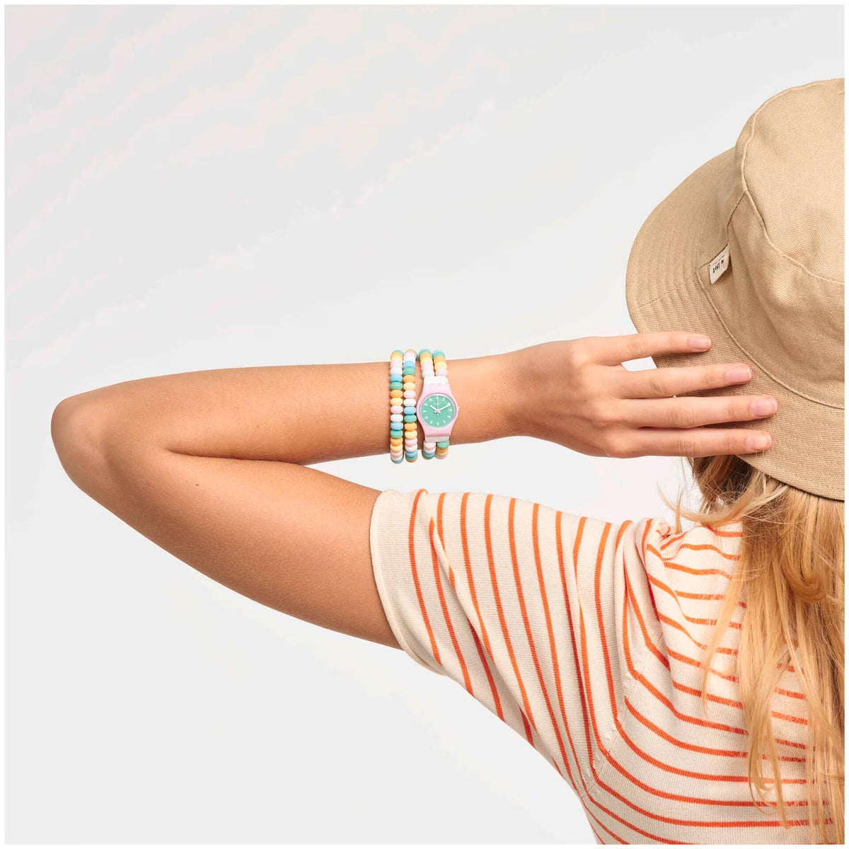 Woman wearing a Swatch quartz watch with green dial and multicolor bead bracelet