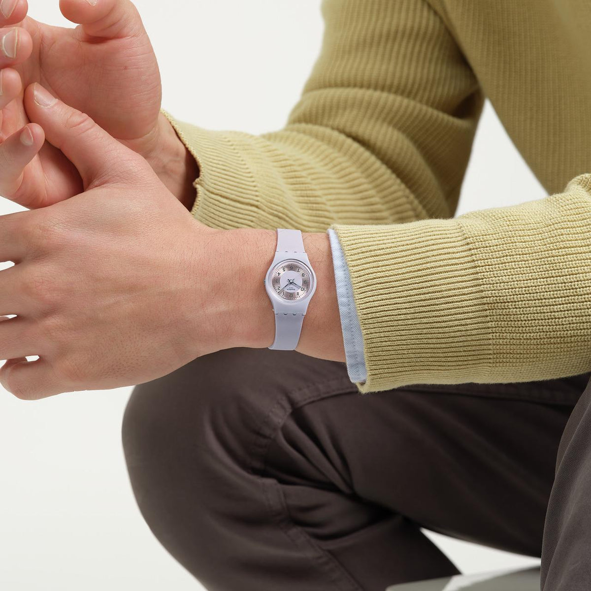 Lilac silicone strap watch on wrist, round pale dial with Swatch logo