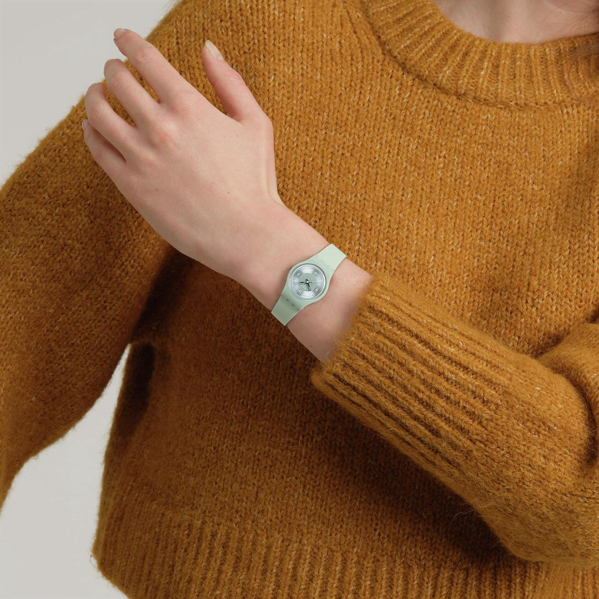 Swatch sage green silicone strap watch worn on wrist with round dial