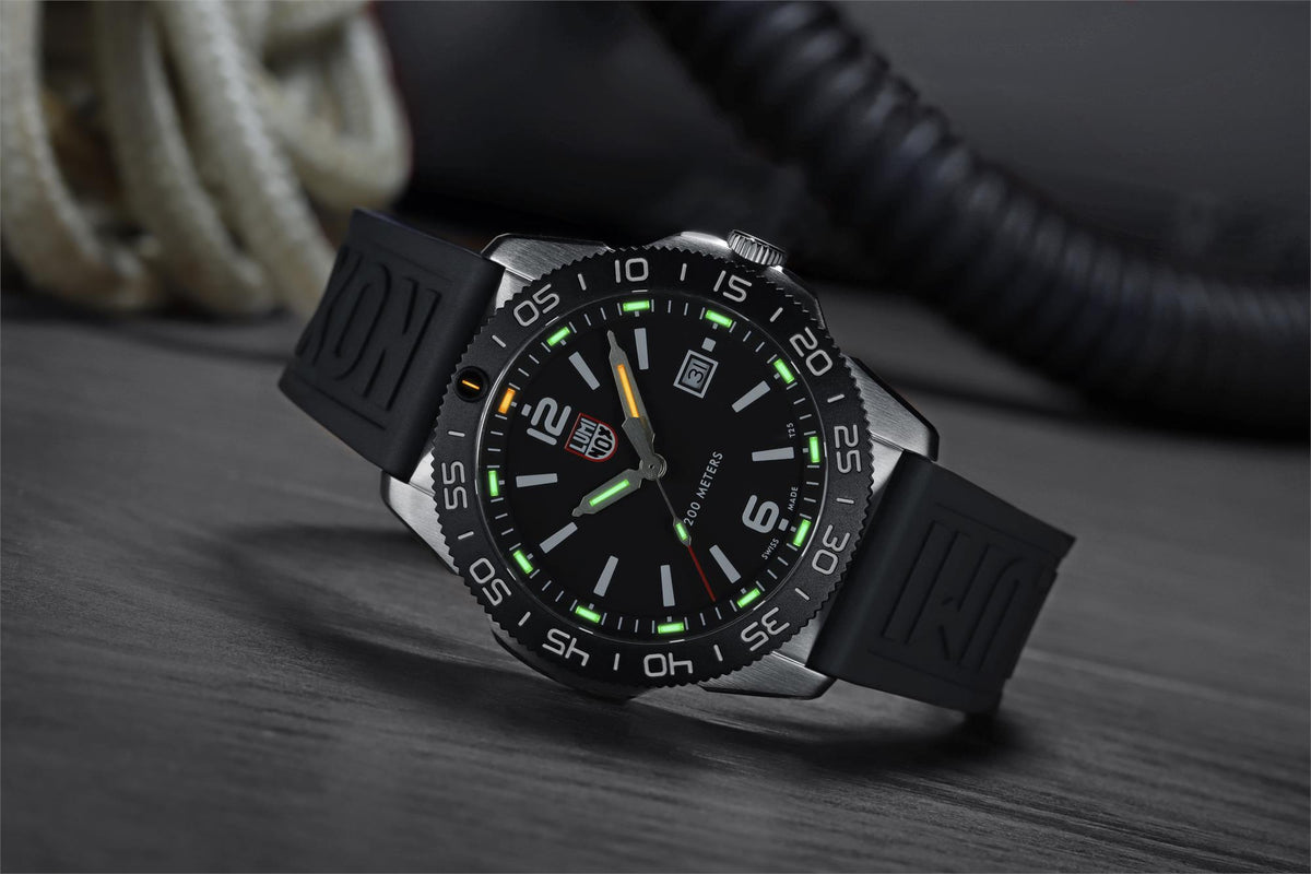 Men's diver watch angled view with green lume dial and black rubber strap.