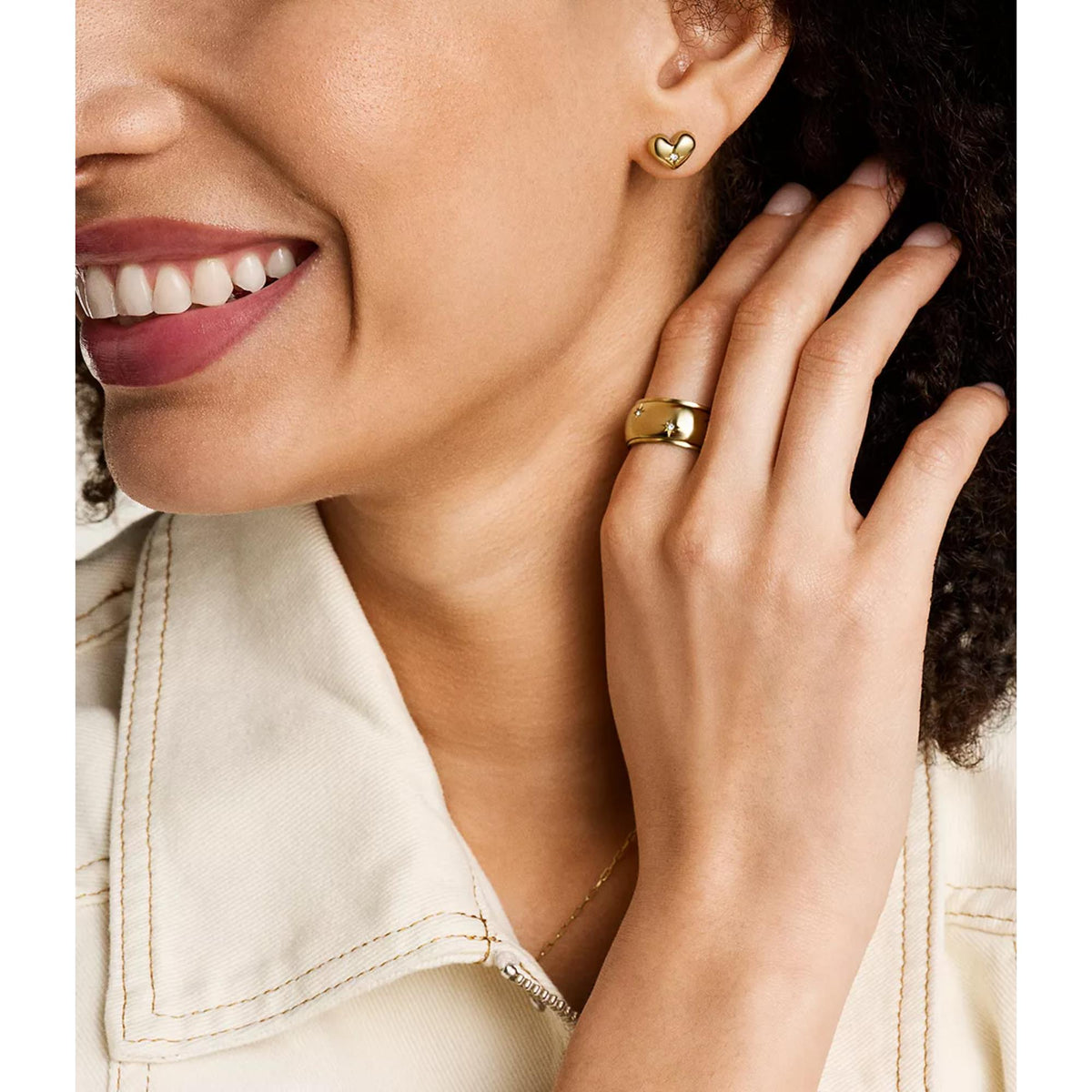 Gold-tone heart stud earrings with small gemstone detail on the ear