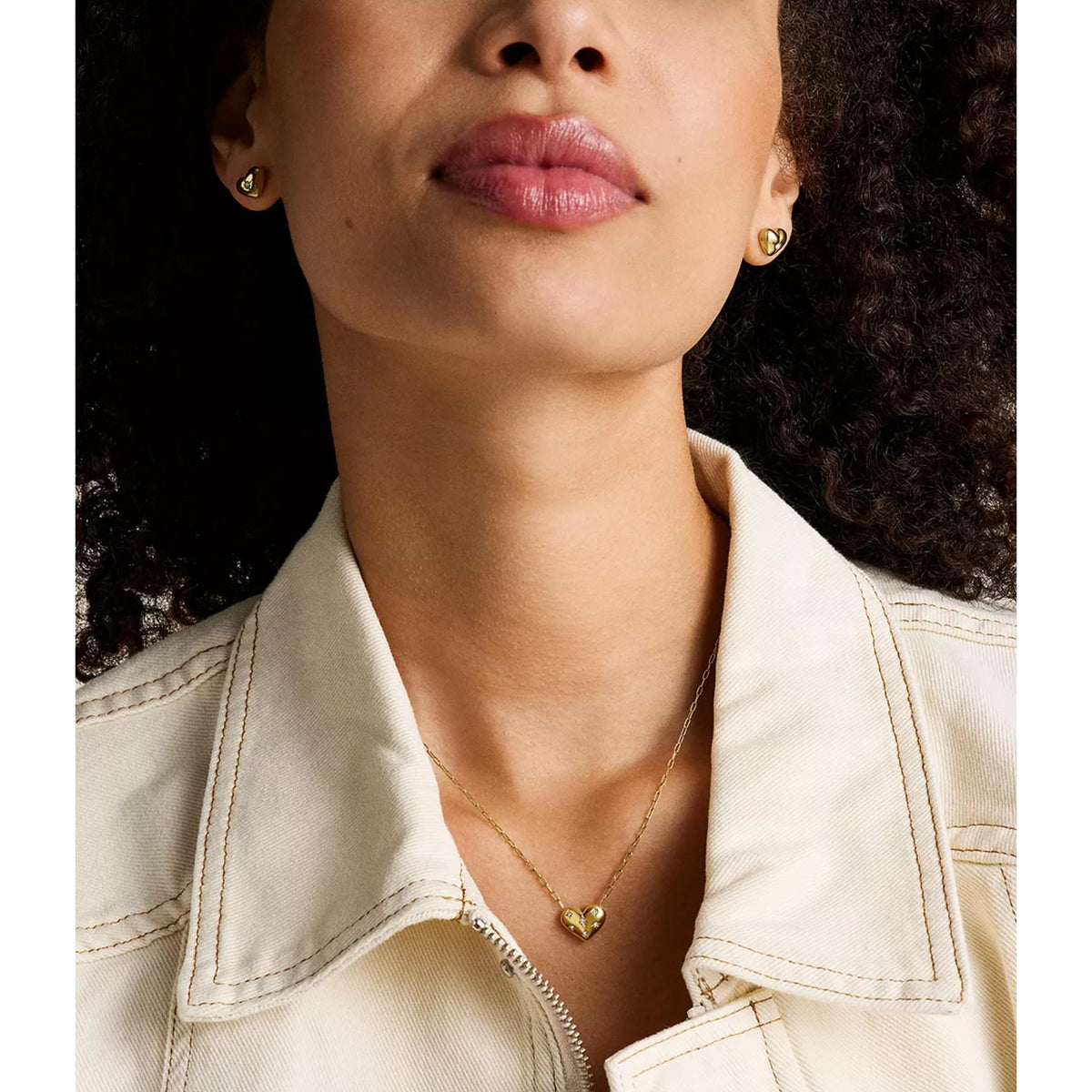 Gold-tone heart stud earrings with gemstone accents near the neckline