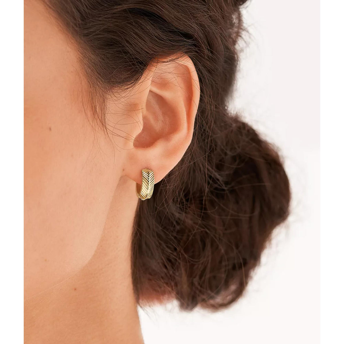 Gold huggie hoop earring with linear chevron texture on ear