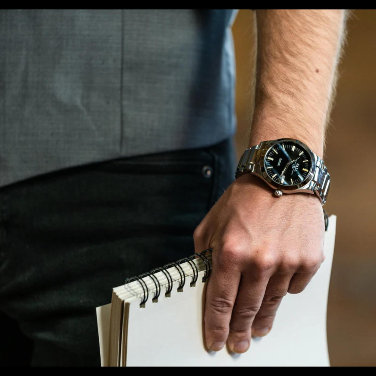 Men's wrist watch on forearm, stainless steel bracelet and black dial