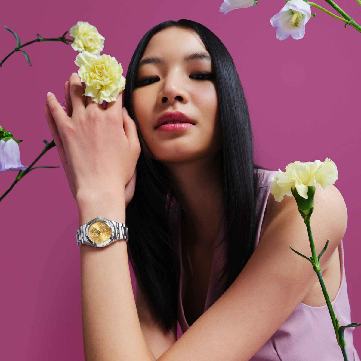 Yellow dial steel strap watch on wrist with silver bracelet visible