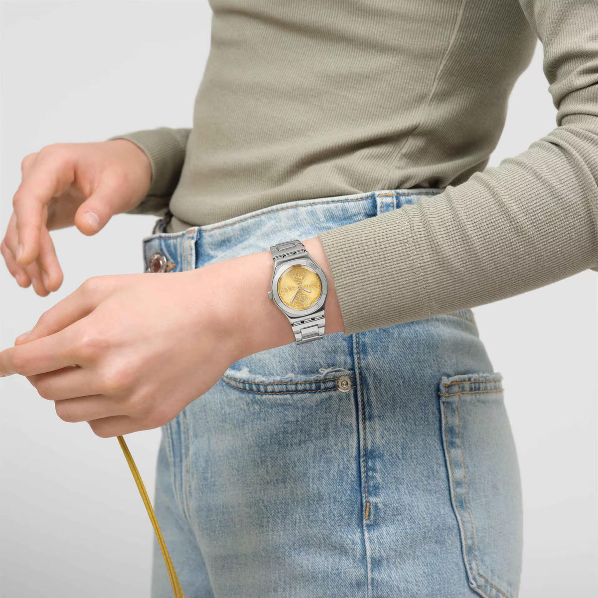 Yellow dial steel strap watch on wrist with silver bracelet visible