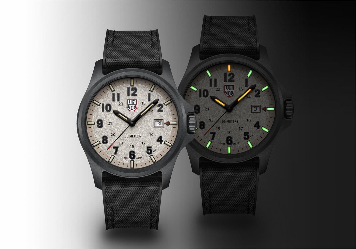 Two black field watches with grey dials, luminous markers, and textured fabric straps