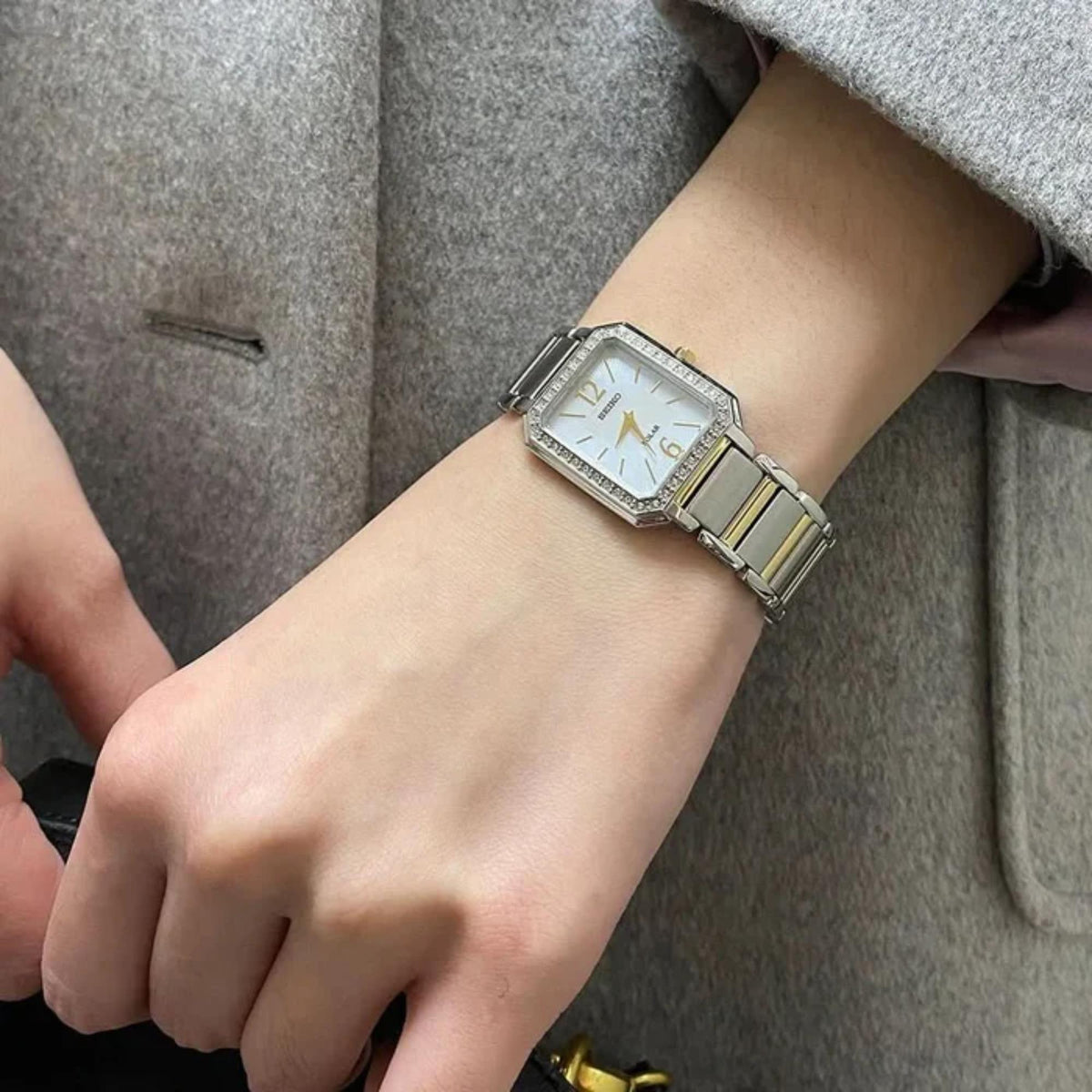 Ladies solar watch on wrist with steel and gold-tone bracelet, mother-of-pearl dial