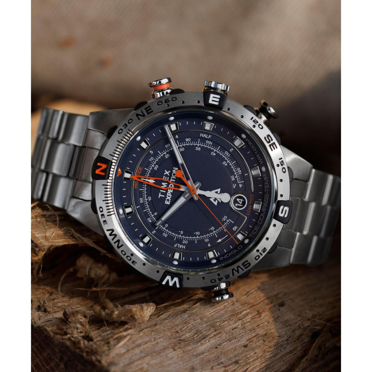 Men's steel quartz watch on wrist with dark blue dial, orange accents, and bezel markings