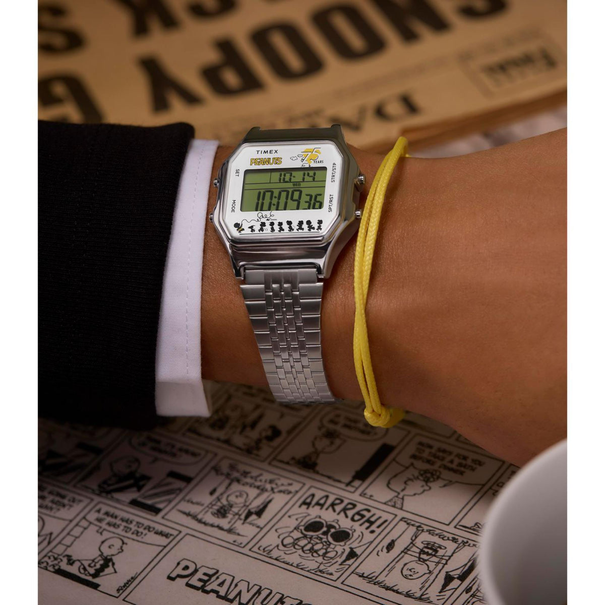 Digital steel-quartz watch worn on wrist with green LCD and Snoopy 75 Years text