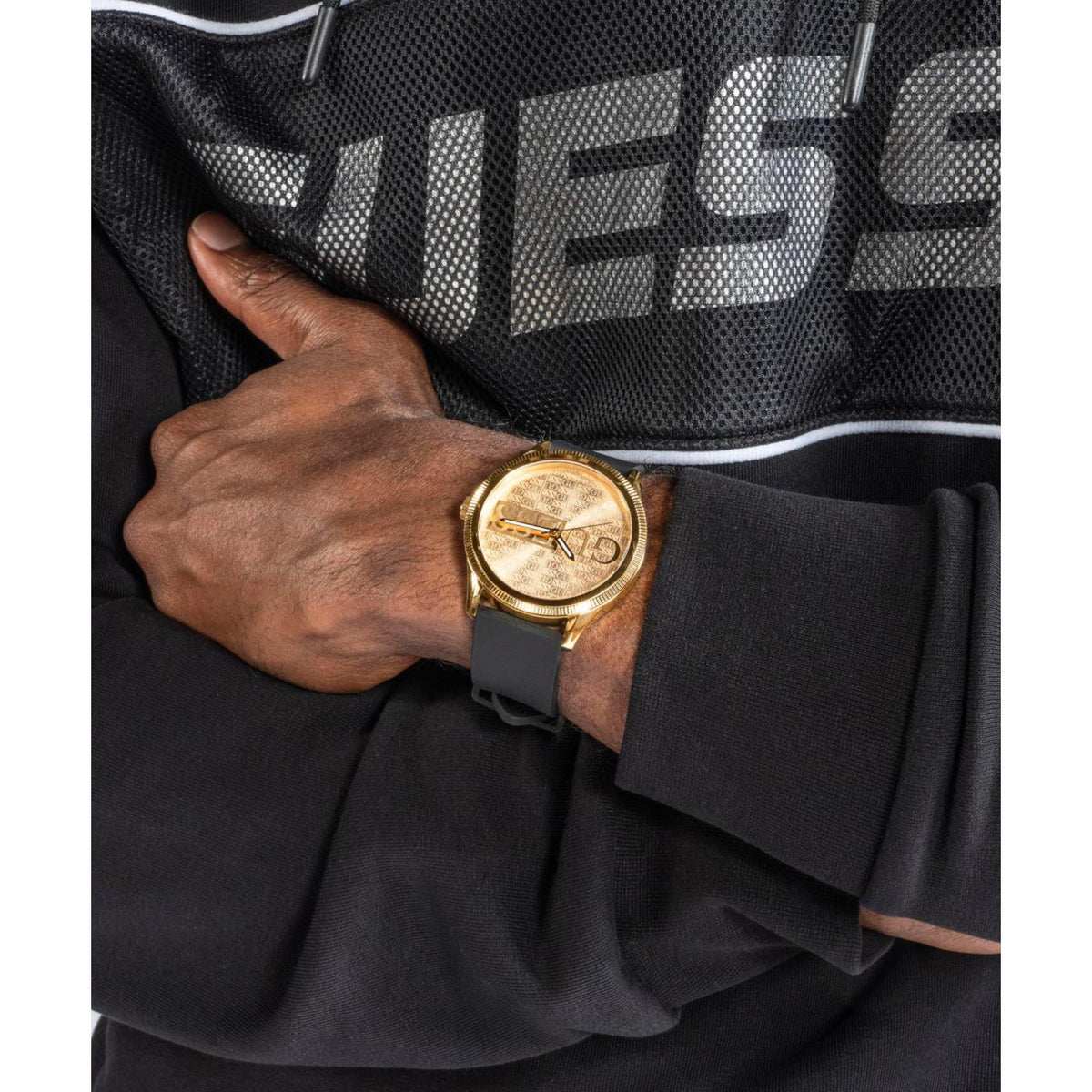 Men's watch on wrist with gold-tone case, champagne dial, and black silicone strap