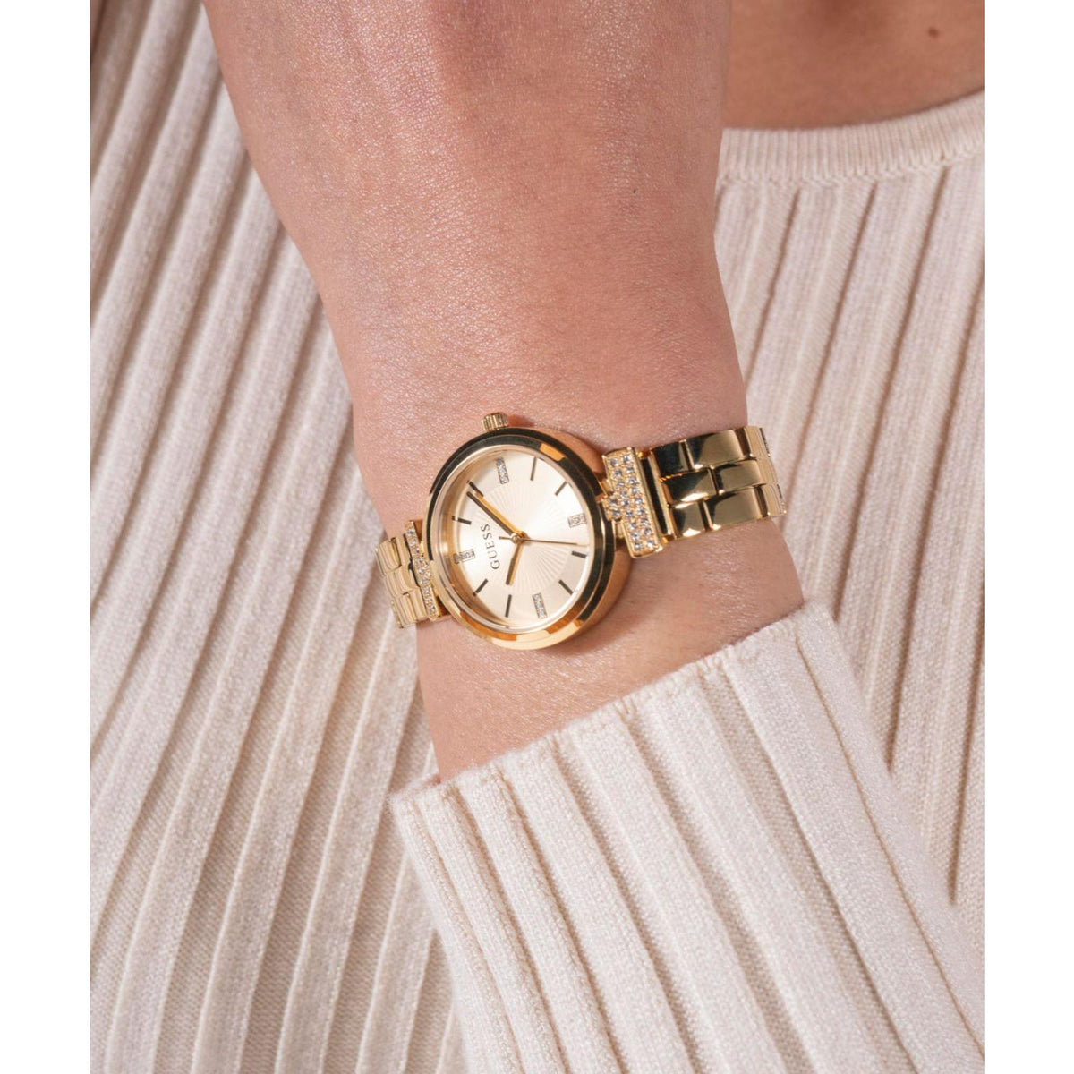 Women’s gold-tone watch with champagne dial and crystal bracelet detail on wrist