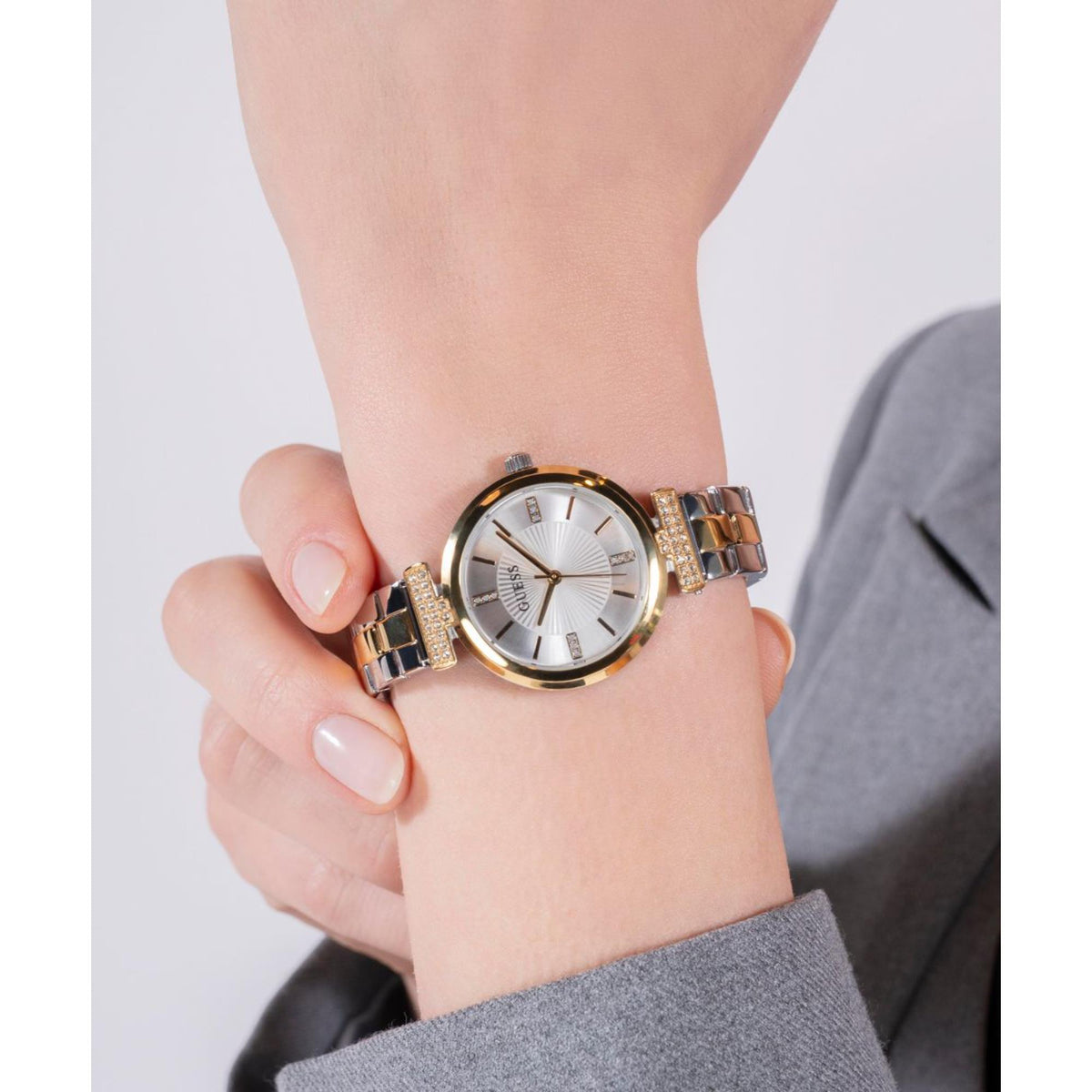 Guess women’s two-tone watch close-up on wrist with white dial and gold-silver bracelet