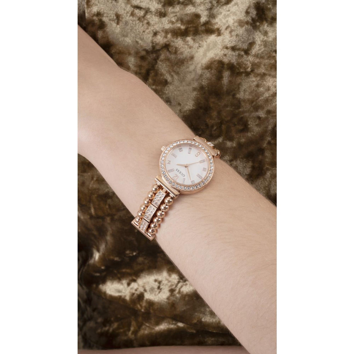 Gold-tone Guess watch worn on wrist, white dial with crystal bezel and pearl-bead strap