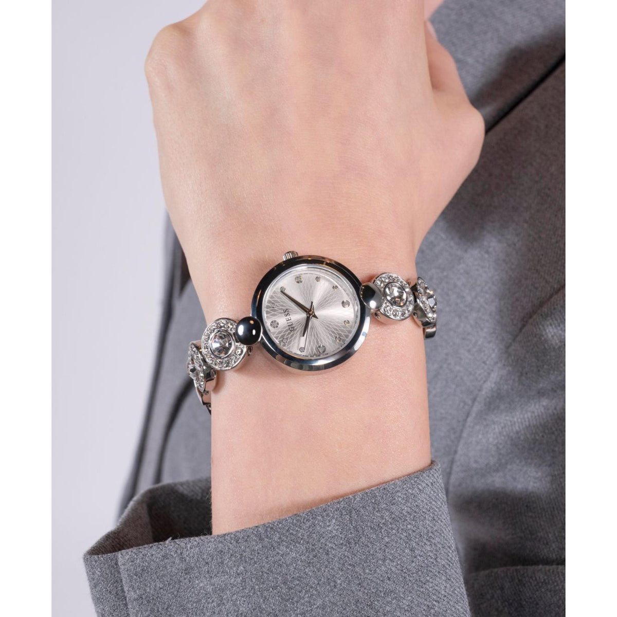 Women’s silver-tone watch on wrist with round gray face and crystal bezel details