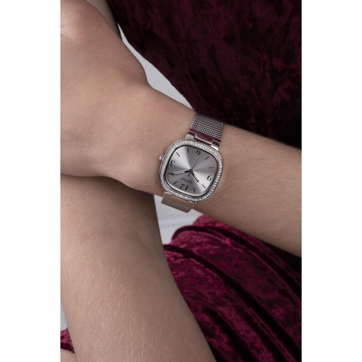Women’s silver mesh strap watch with rounded square dial and crystal bezel on wrist
