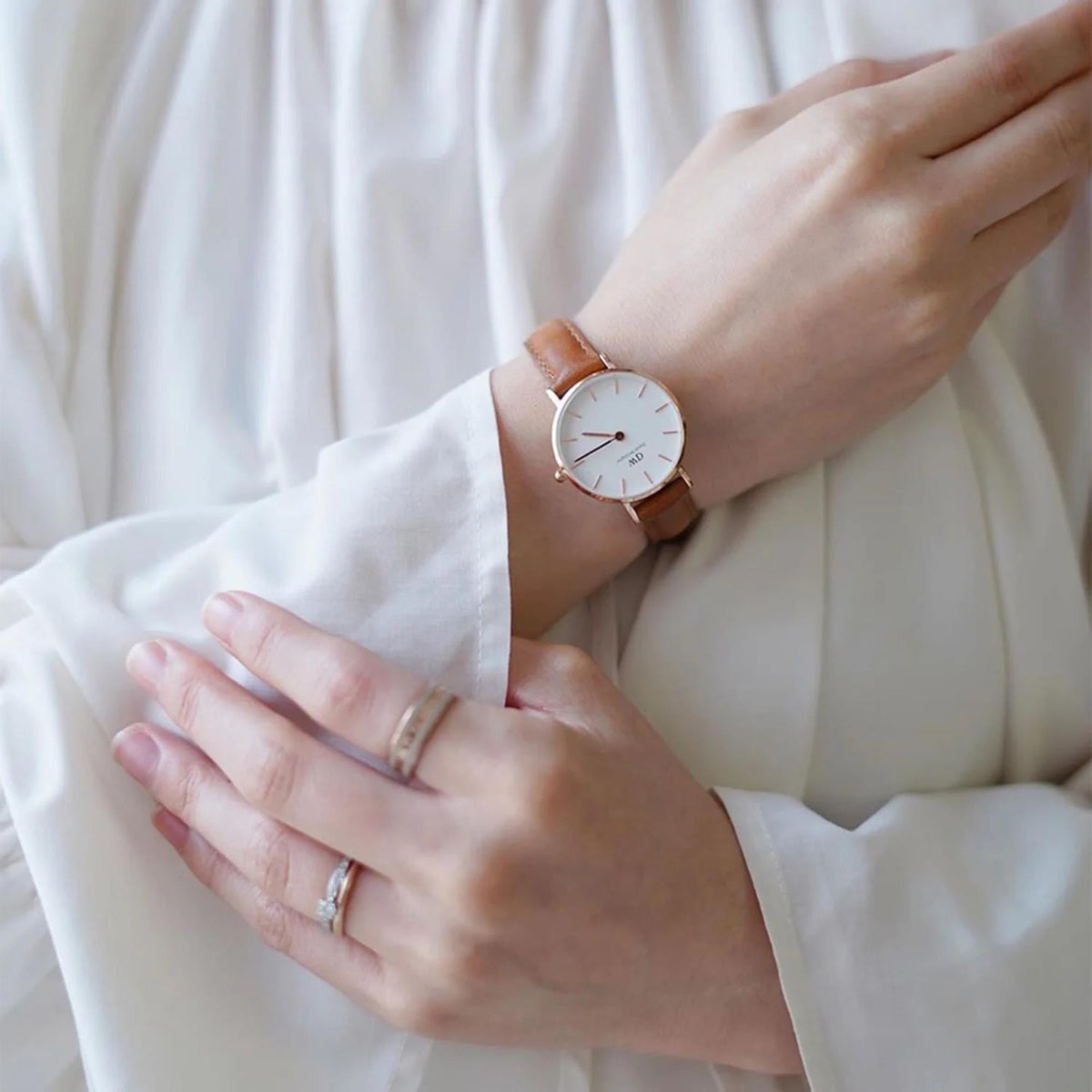 Petite quartz watch worn on wrist, white dial with rose gold markers and hands