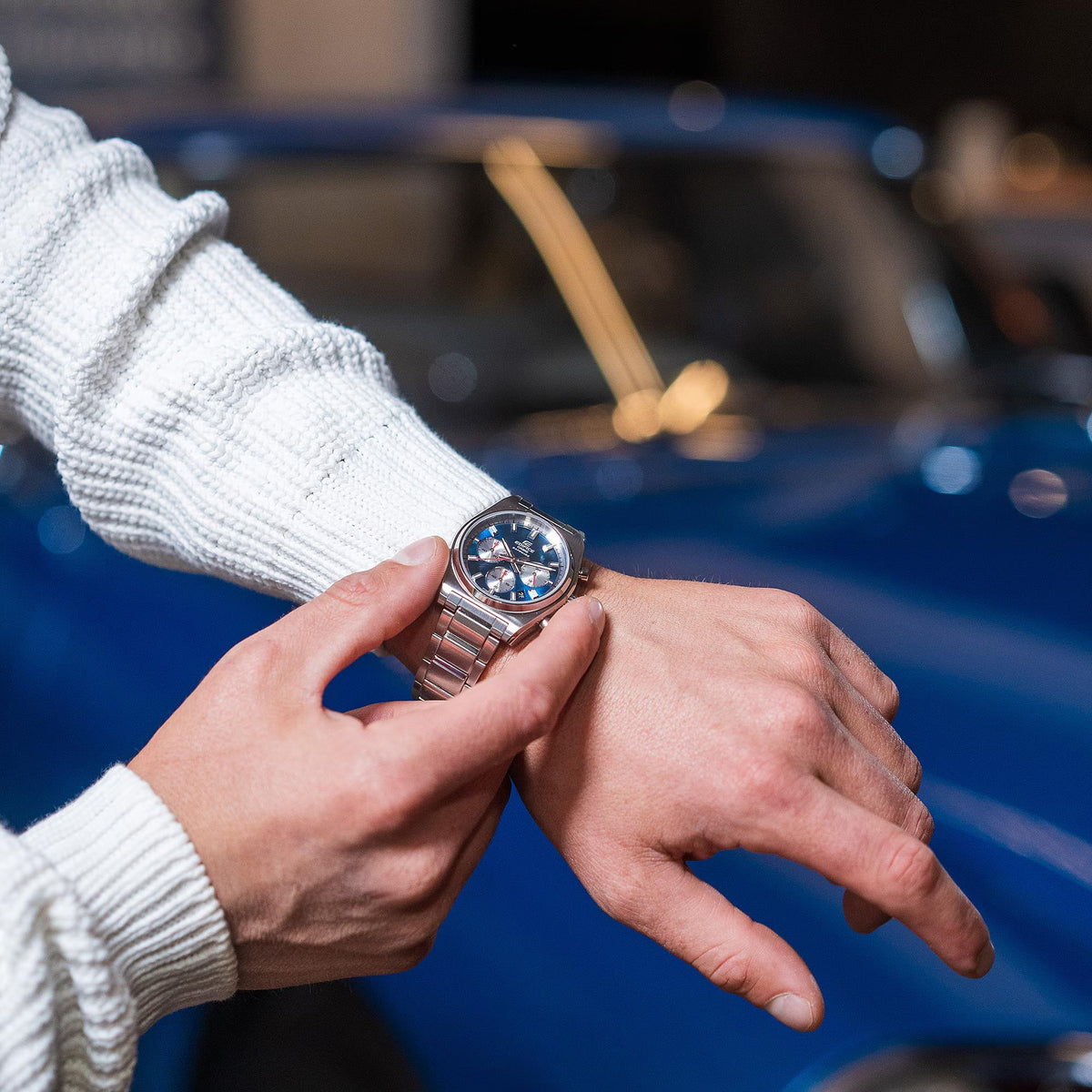 Stainless steel chronograph watch with blue dial and subdials held in hands