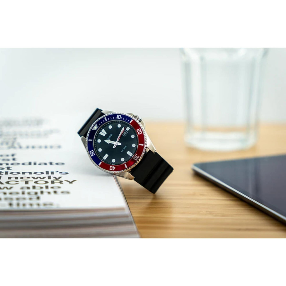 Casio Marlin MDV-107-1A3VEF black dial dive watch resting upright on a wooden desk next to a book
