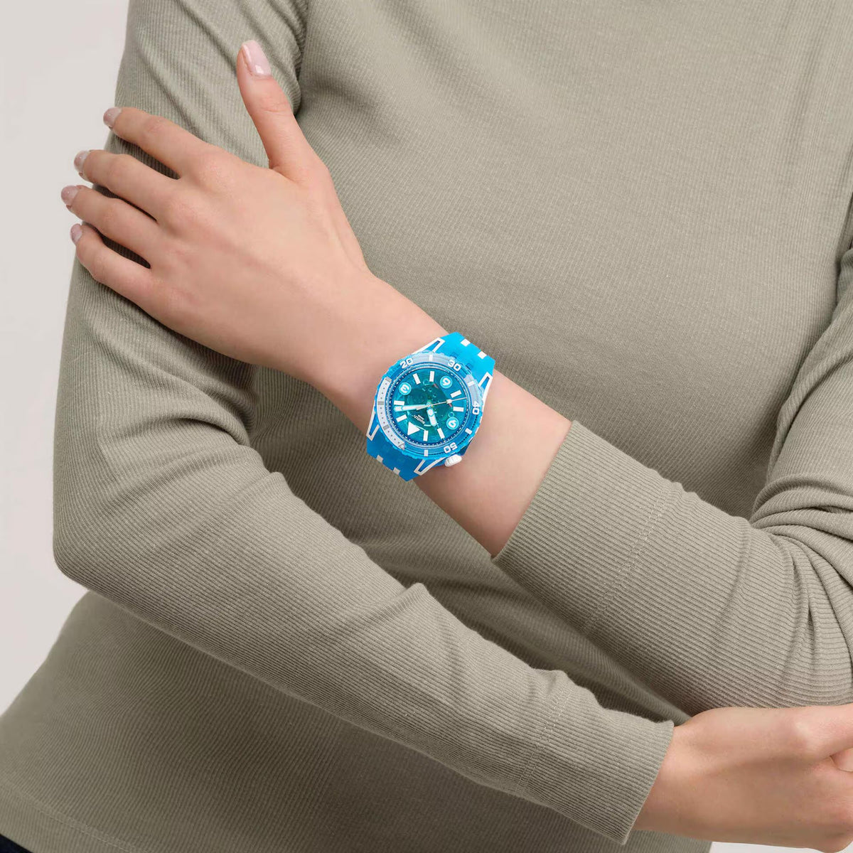 Blue silicone-strap watch on arm sleeve, blue dial with white hour markers and hands