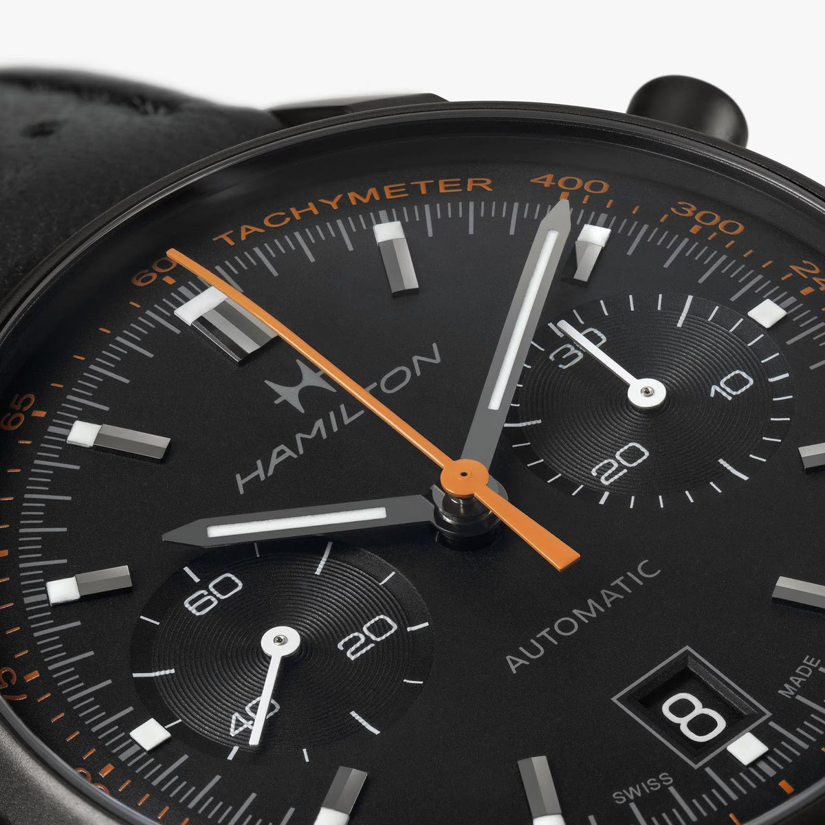 Close-up of black dial chronograph watch with orange second hand and tachymeter scale