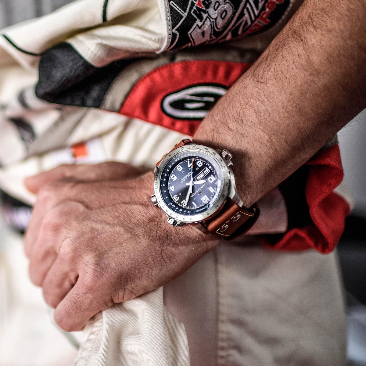 Hamilton pilot watch on wrist with blue dial and brown leather strap, steel case details