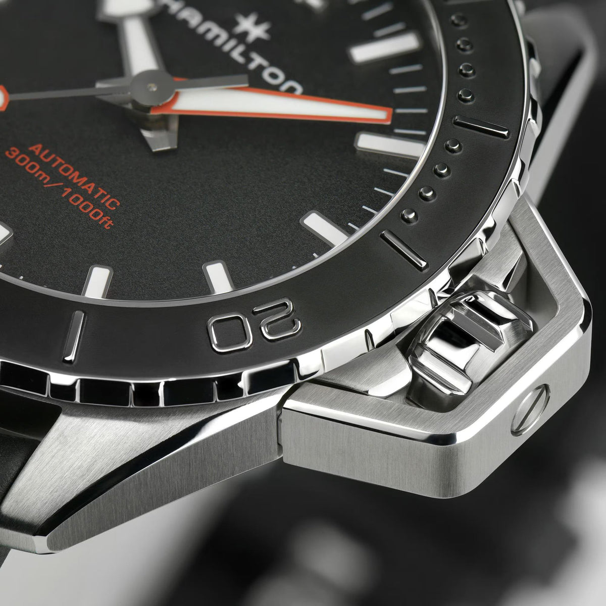 Close-up of black bezel and stainless steel case with rubber strap and crown area