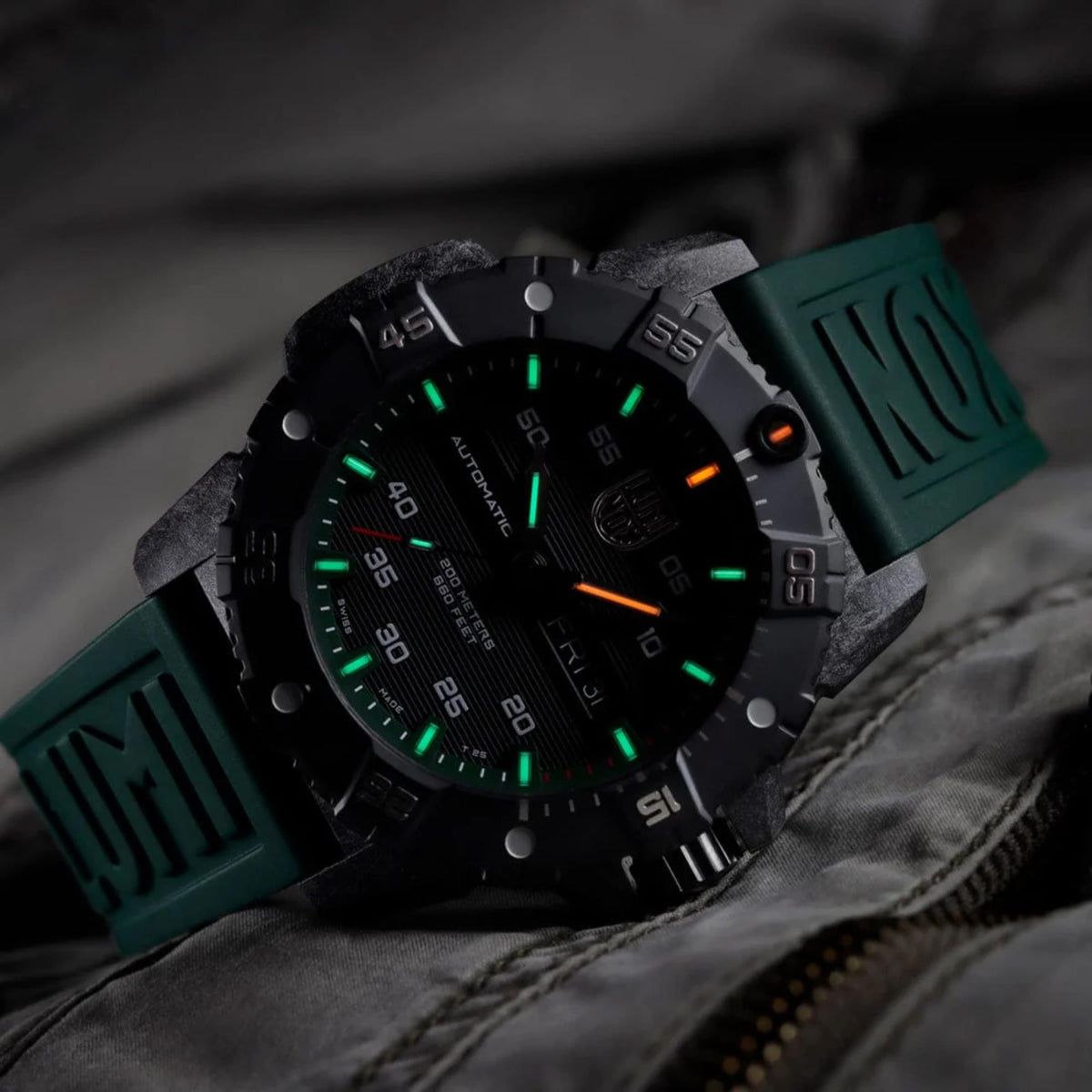 Men's automatic dive watch close-up with black dial, orange marker, and green rubber strap