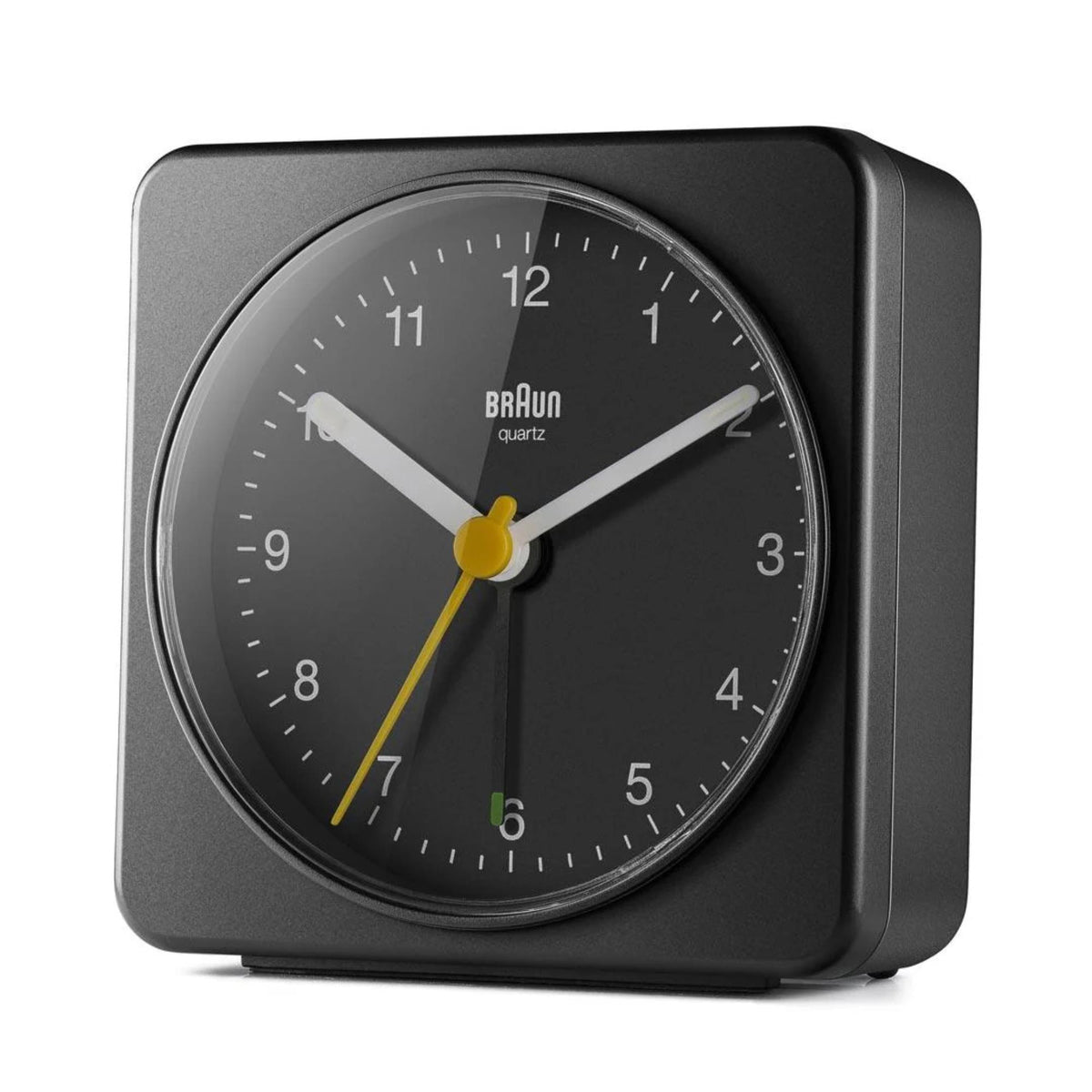 Black Braun quartz alarm clock with yellow hands and round glass dial, angled view