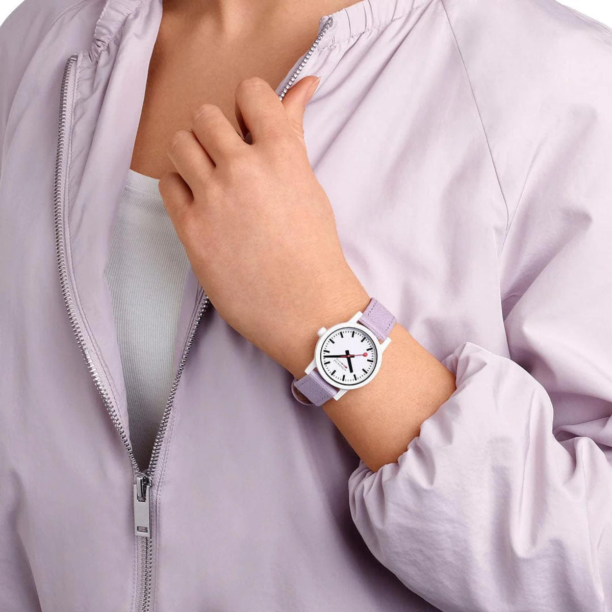 Women’s quartz watch on wrist with lavender strap and white dial, worn with jacket