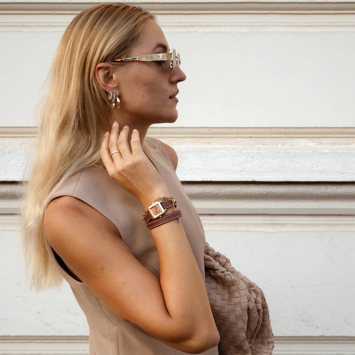 Women’s brown leather strap square watch with gold-toned case on wrist, side view