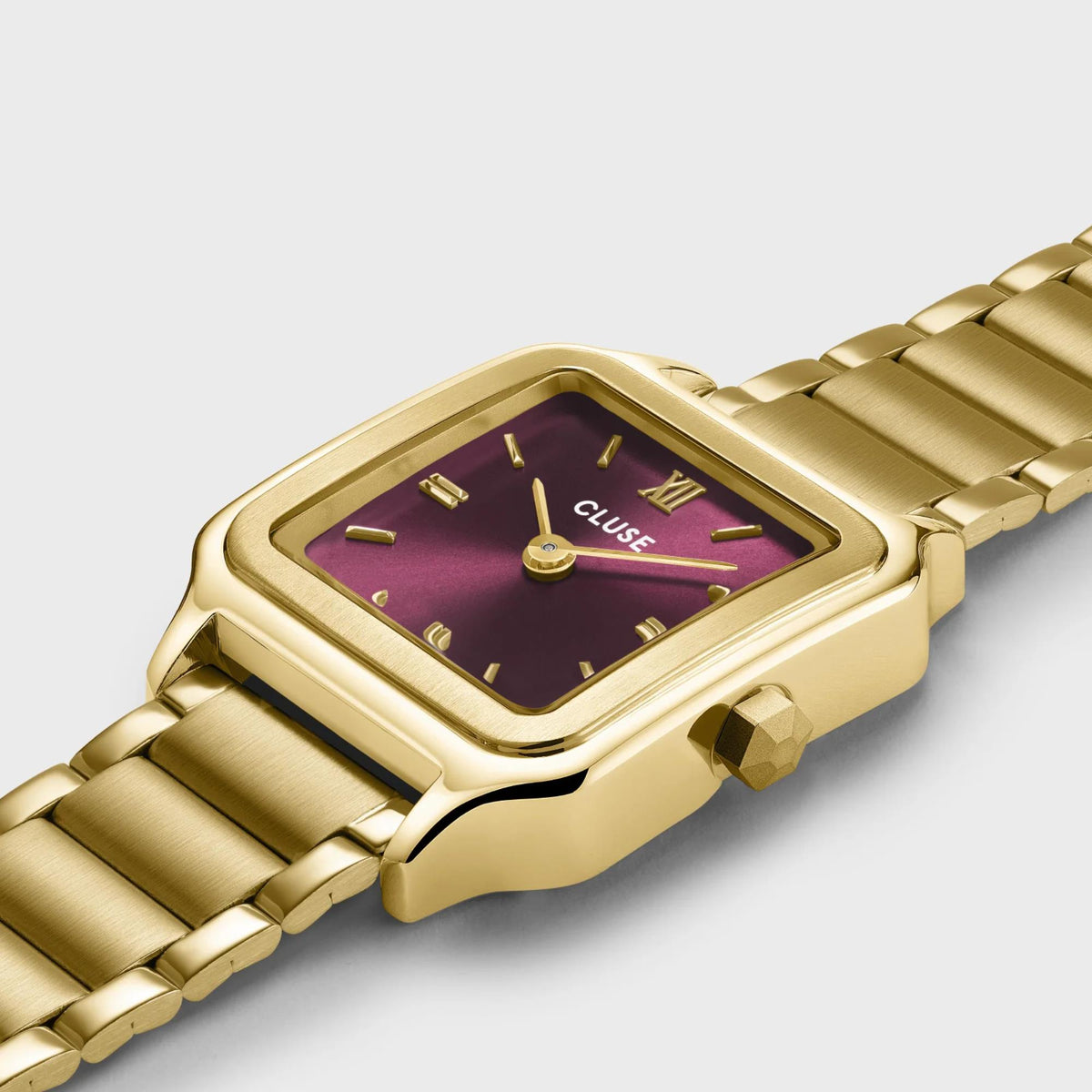 Gold-tone steel strap quartz watch with purple-red dial and square case