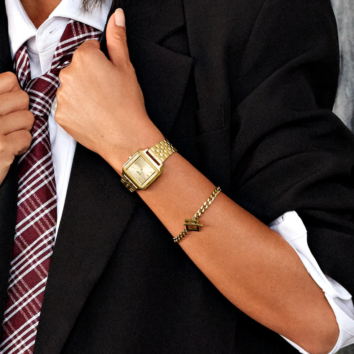Gold-tone square quartz watch on wrist with white dial and metal bracelet strap