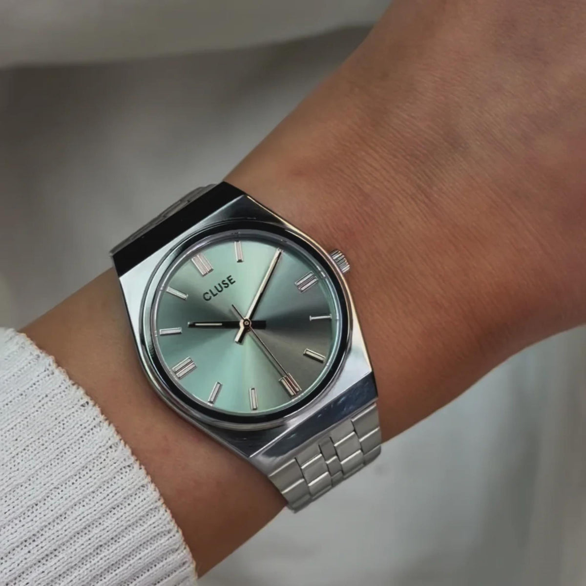 Close-up of stainless steel watch showing mint-green dial and rose gold hour markers