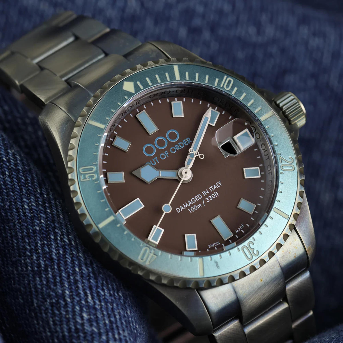 Men's quartz watch on denim with brown dial, luminous hour markers, metal bracelet