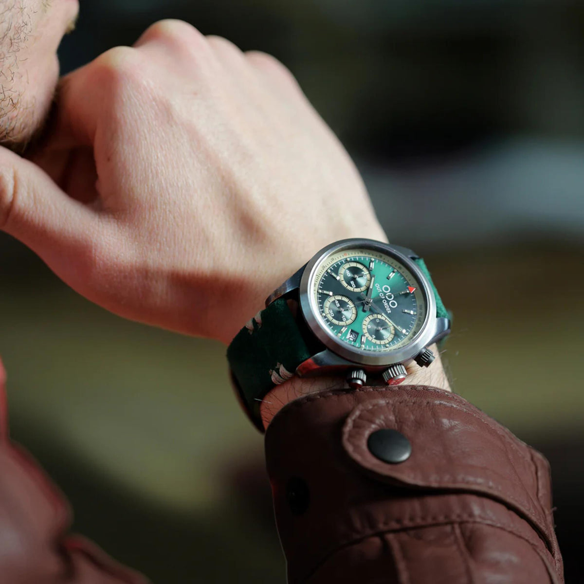 Men's sporty quartz chronograph watch on wrist with green dial and brown leather strap.