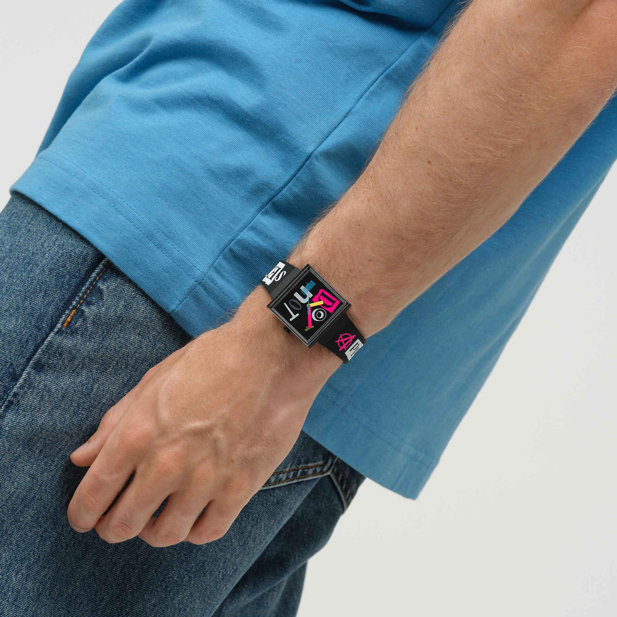 Black silicone strap square watch on wrist, black dial with colorful graphic details