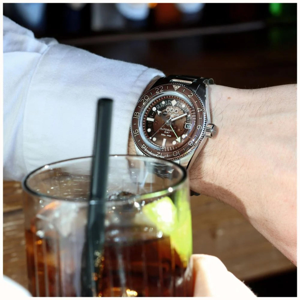 Men's automatic steel wristwatch on wrist with brown dial and polished metal bracelet