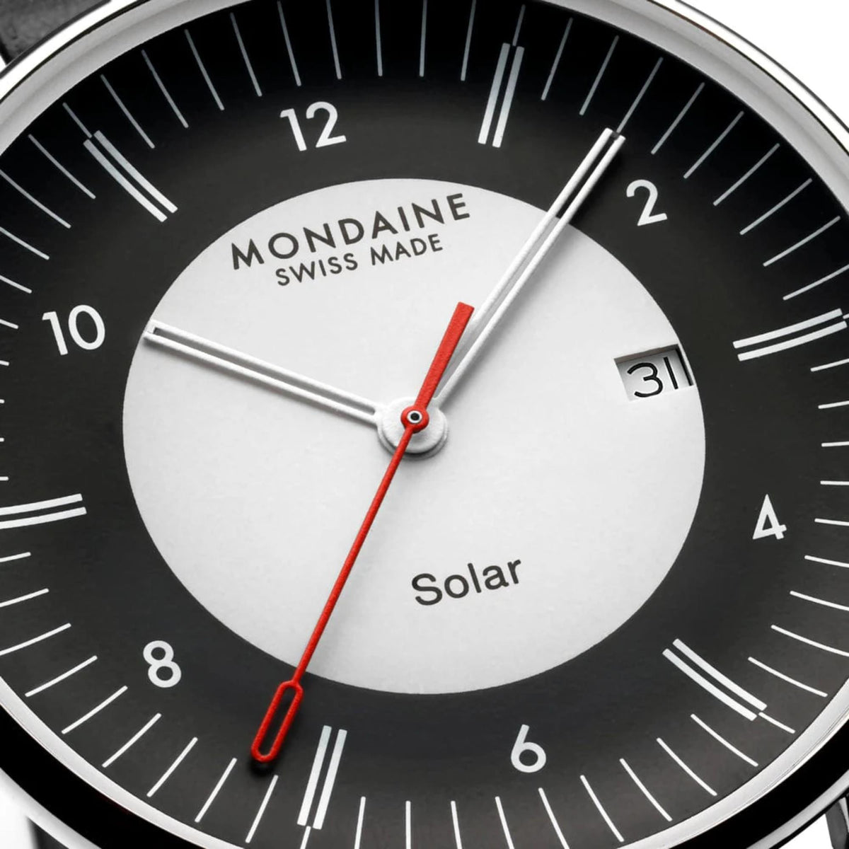 Close-up of watch dial, showing the central white 'Solar' circle, black outer ring with white hour markers, date window at 3 o'clock, and signature red second hand