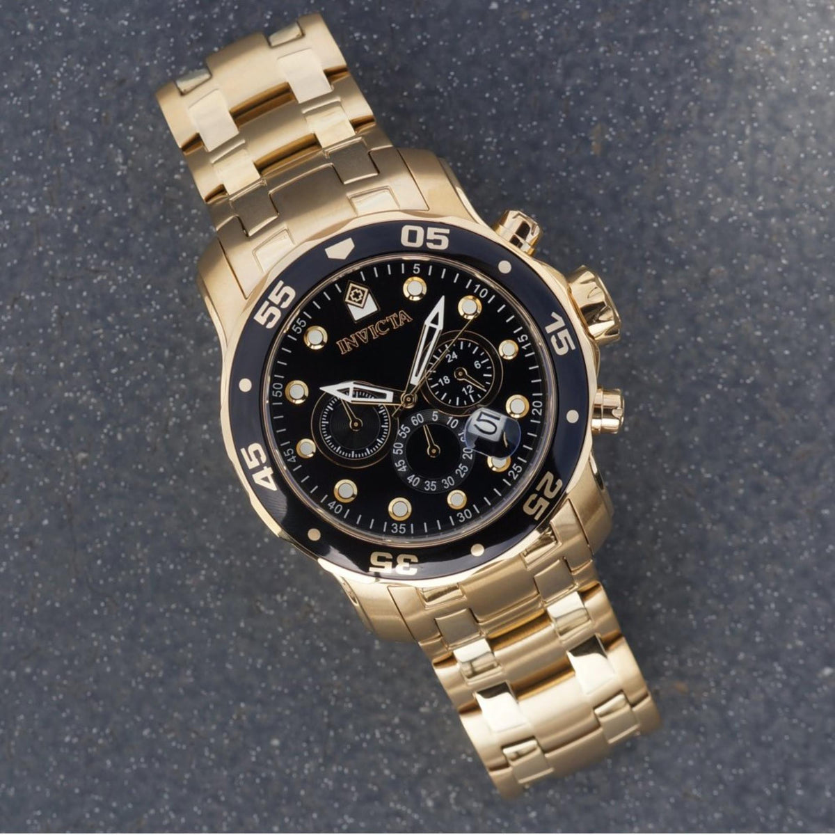 Men's Invicta Pro Diver chronograph watch on dark strap, black dial, gold-tone bracelet.