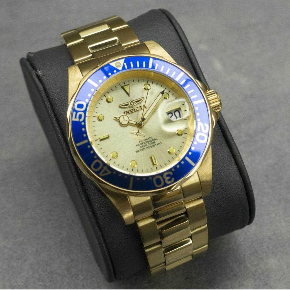 Gold-tone steel diver watch on black strap, champagne dial with blue bezel and date window