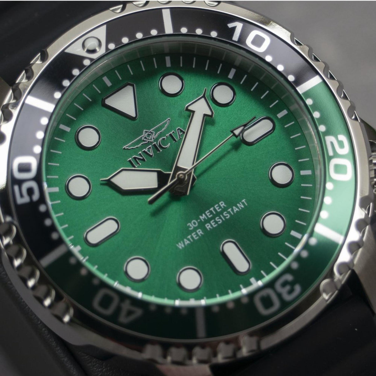 Men's dive watch close-up: green dial with lumed markers, stainless bezel, black silicone strap