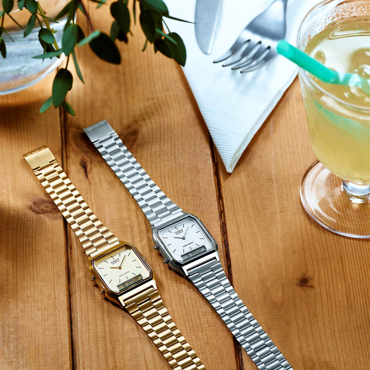 Silver steel strap quartz watch with white dial, beside a gold-tone watch