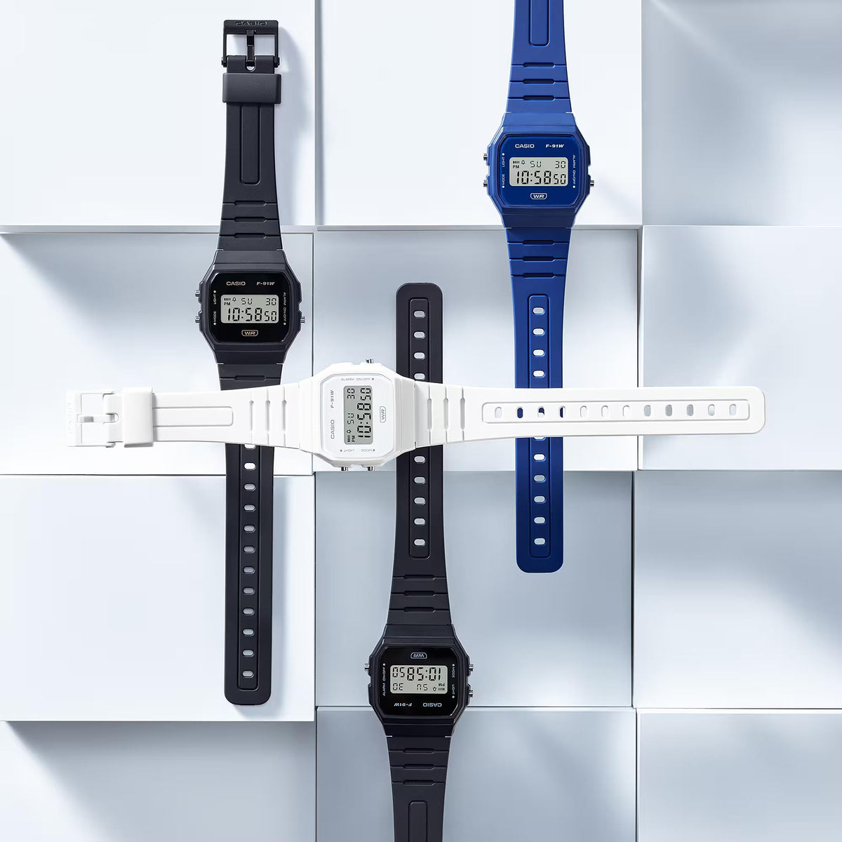 Resin strap digital quartz watches in black, blue, and white on a display stand