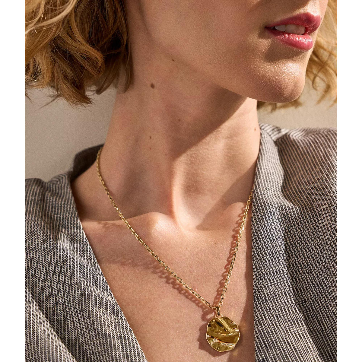 Gold-tone stainless steel pendant necklace with round textured disc centerpiece