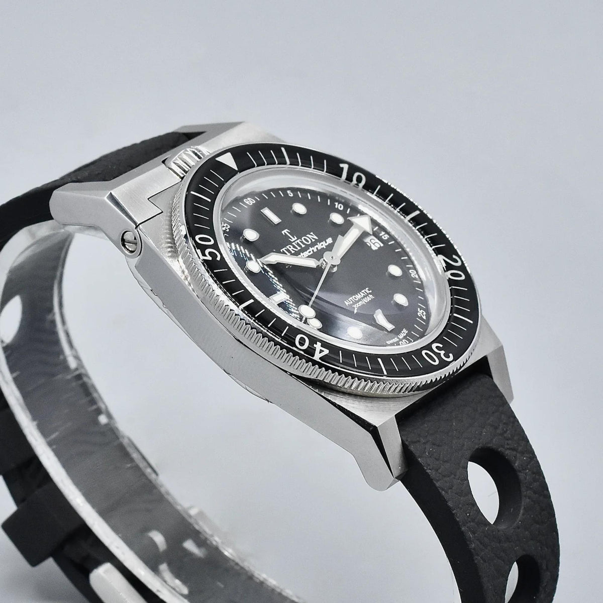 Men's dive watch profile, steel case with crown, black rubber strap with oval cutouts.