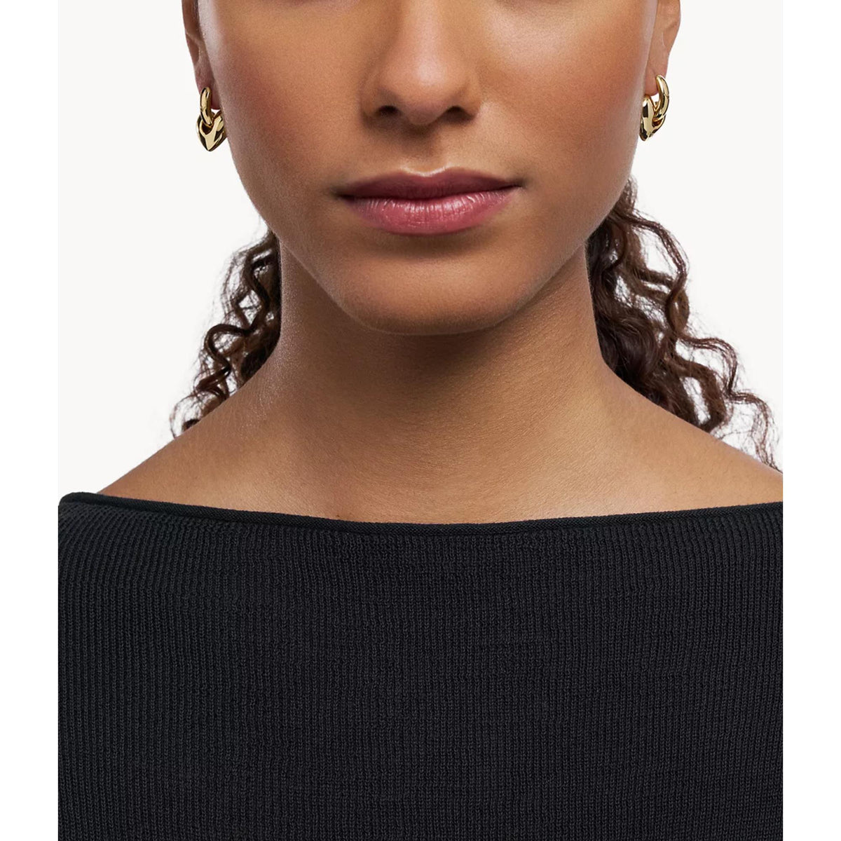 Frontal portrait view of model wearing Emporio Armani women's gold-tone heart hoop earrings EGS3266710